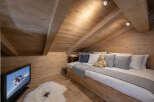 This cozy attic bedroom features a warm, inviting wooden interior, perfect for a relaxing retreat.