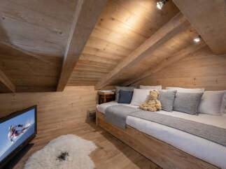 This cozy attic bedroom features a warm, inviting wooden interior, perfect for a relaxing retreat.