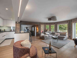 Experience luxury living in this stunning property, featuring a modern kitchen with sleek white cabinetry and a cozy living area with a plush sectional sofa.
