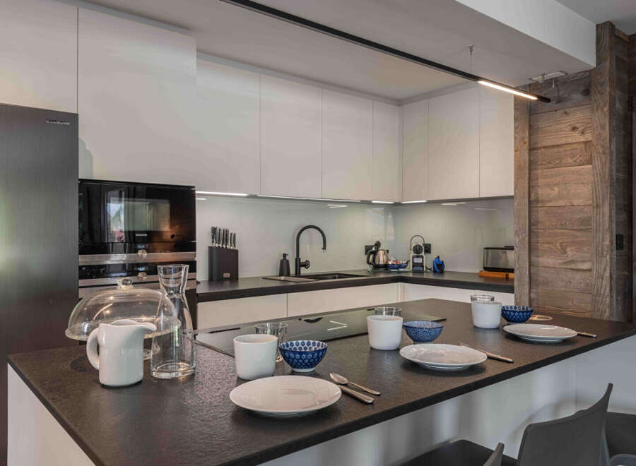 This modern kitchen boasts sleek, white cabinetry and a dark countertop, creating a sophisticated contrast.