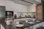 This modern kitchen boasts sleek, white cabinetry and a dark countertop, creating a sophisticated contrast.