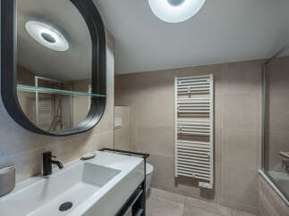 Step into a modern bathroom oasis! This stunning space features a sleek, minimalist design with a stylish vanity and a large, oval mirror.
