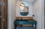 This modern bathroom features a stylish teal sink and a sleek, oval-shaped mirror.