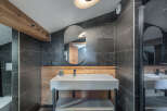 This modern bathroom features a sleek design with dark tiled walls and a stylish vanity.
