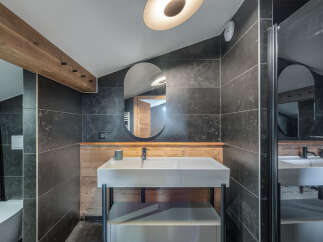 This modern bathroom features a sleek design with dark tiled walls and a stylish vanity.