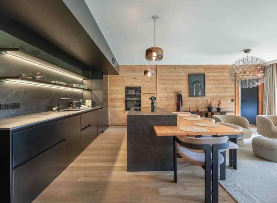 Experience modern luxury in this stunning kitchen, featuring sleek black cabinetry and a contrasting wooden accent wall.