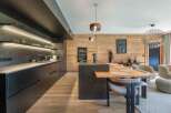 Experience modern luxury in this stunning kitchen, featuring sleek black cabinetry and a contrasting wooden accent wall.
