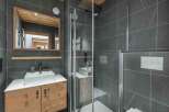 Step into a modern bathroom oasis, featuring sleek gray tile and a stylish wooden vanity.