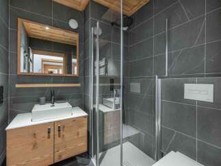 Step into a modern bathroom oasis, featuring sleek gray tile and a stylish wooden vanity.