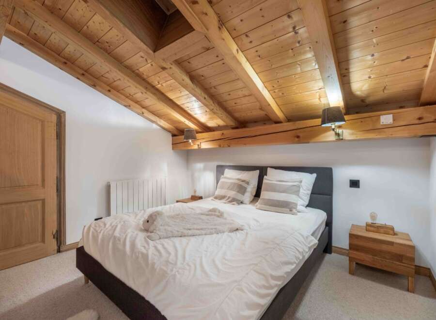 Experience rustic charm in this cozy bedroom featuring a stunning wooden ceiling and exposed beams.