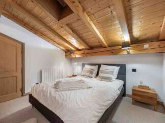 Experience rustic charm in this cozy bedroom featuring a stunning wooden ceiling and exposed beams.