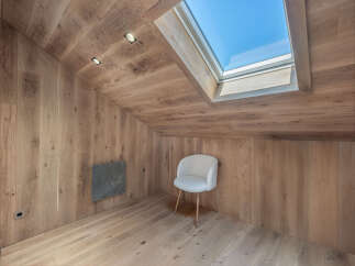 This stunning attic space boasts a warm and inviting ambiance with its natural wood paneling and flooring.