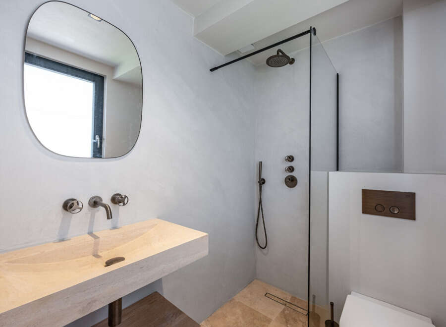 This modern bathroom features a sleek design with a stone sink and a walk-in shower.