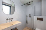 This modern bathroom features a sleek design with a stone sink and a walk-in shower.