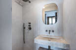 This modern bathroom features a sleek, minimalist design with a concrete sink and a unique, rounded mirror.