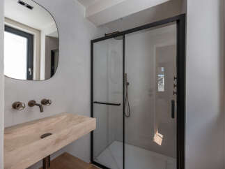 Step into a modern bathroom oasis, featuring a sleek glass shower enclosure and a stylish stone sink.