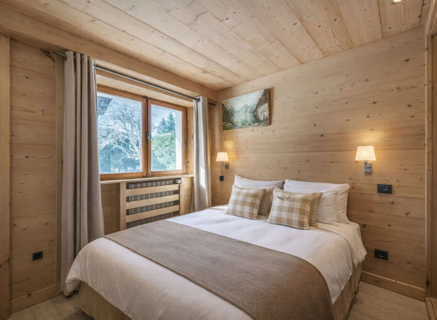 This cozy bedroom features a warm, inviting atmosphere with its wooden walls and ceiling.