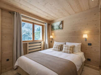 This cozy bedroom features a warm, inviting atmosphere with its wooden walls and ceiling.