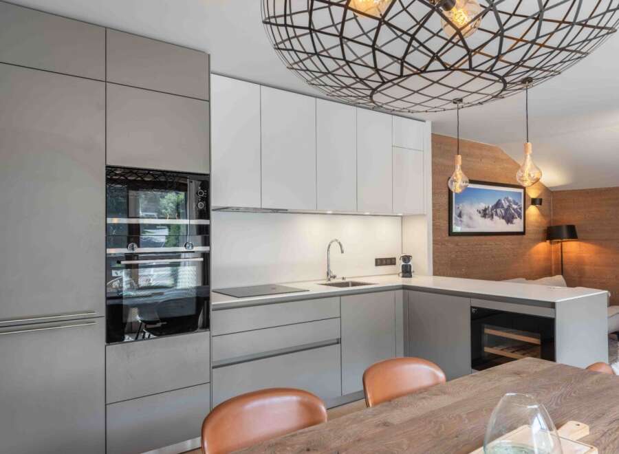 This modern kitchen boasts sleek cabinetry, stainless steel appliances, and a stunning geometric light fixture.