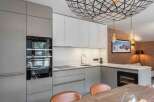 This modern kitchen boasts sleek cabinetry, stainless steel appliances, and a stunning geometric light fixture.