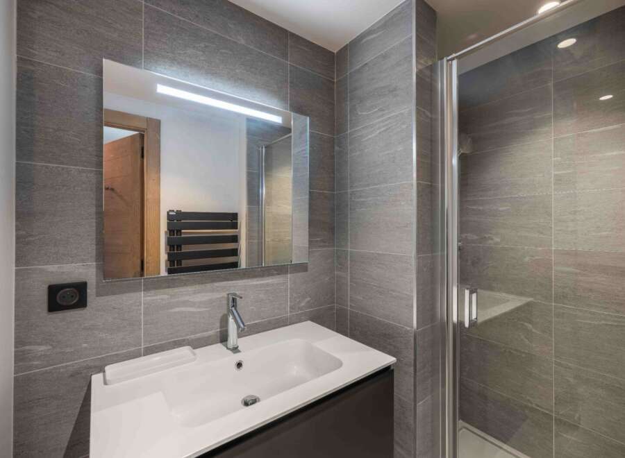 This modern bathroom features sleek gray tile, a spacious shower, and a stylish vanity.