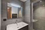 This modern bathroom features sleek gray tile, a spacious shower, and a stylish vanity.