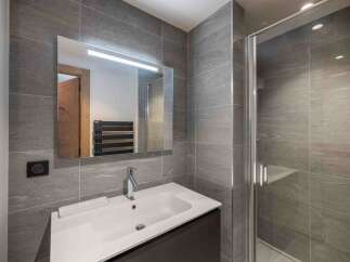 This modern bathroom features sleek gray tile, a spacious shower, and a stylish vanity.