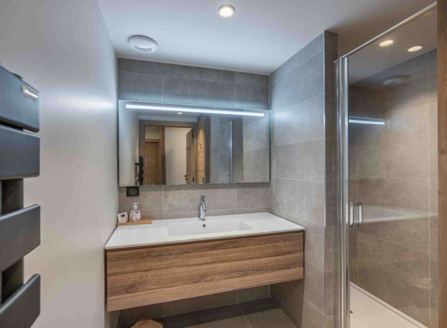 This modern bathroom features a sleek design with a wooden vanity and a large mirror.