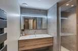 This modern bathroom features a sleek design with a wooden vanity and a large mirror.