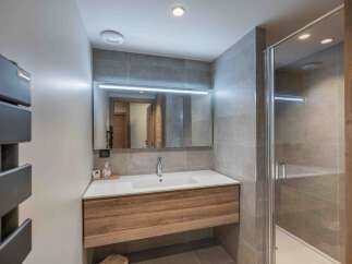 This modern bathroom features a sleek design with a wooden vanity and a large mirror.