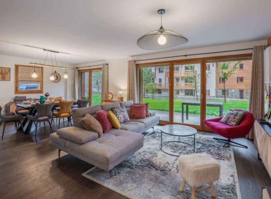 Experience luxury living in this stunning property, featuring a spacious living area with a modern sectional sofa and a cozy red armchair.