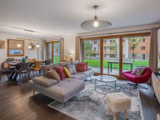Experience luxury living in this stunning property, featuring a spacious living area with a modern sectional sofa and a cozy red armchair.