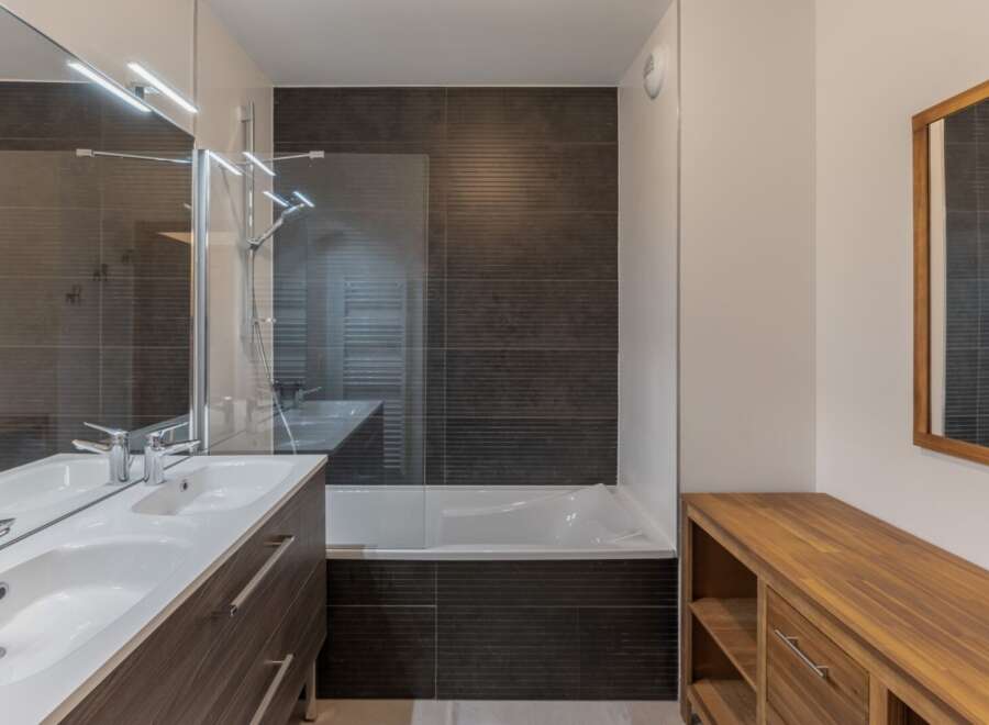 This modern bathroom features a sleek design with dark tile accents and a spacious vanity.