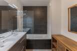 This modern bathroom features a sleek design with dark tile accents and a spacious vanity.