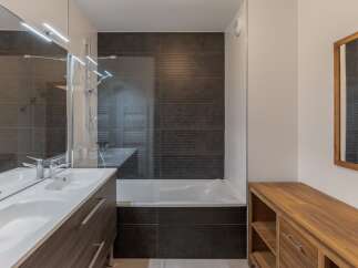 This modern bathroom features a sleek design with dark tile accents and a spacious vanity.