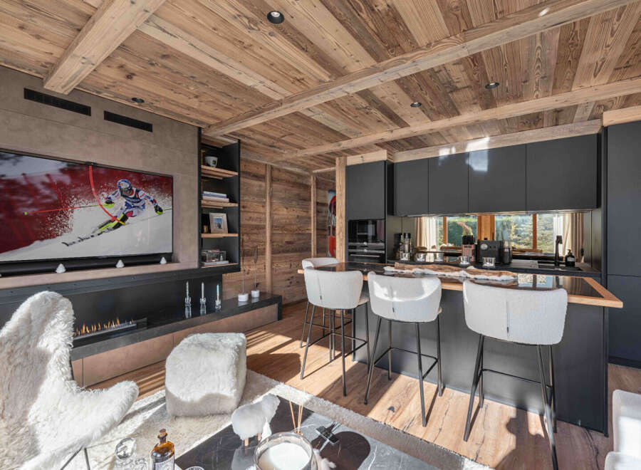 Experience luxury living in this stunning property featuring a modern kitchen with sleek black cabinetry and a cozy living area.