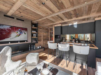 Experience luxury living in this stunning property featuring a modern kitchen with sleek black cabinetry and a cozy living area.
