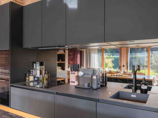 Experience modern luxury in this stunning kitchen, featuring sleek black cabinetry and a minimalist design.