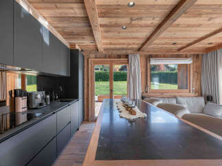 This stunning kitchen showcases a modern design with sleek black cabinetry and a contrasting wooden ceiling, creating a warm and inviting atmosphere.