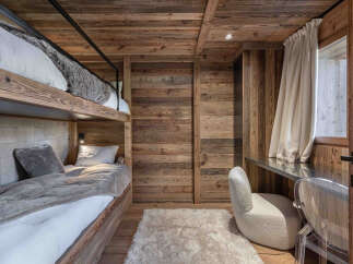 This cozy bedroom features a unique bunk bed design with wooden paneling, creating a warm and inviting atmosphere.