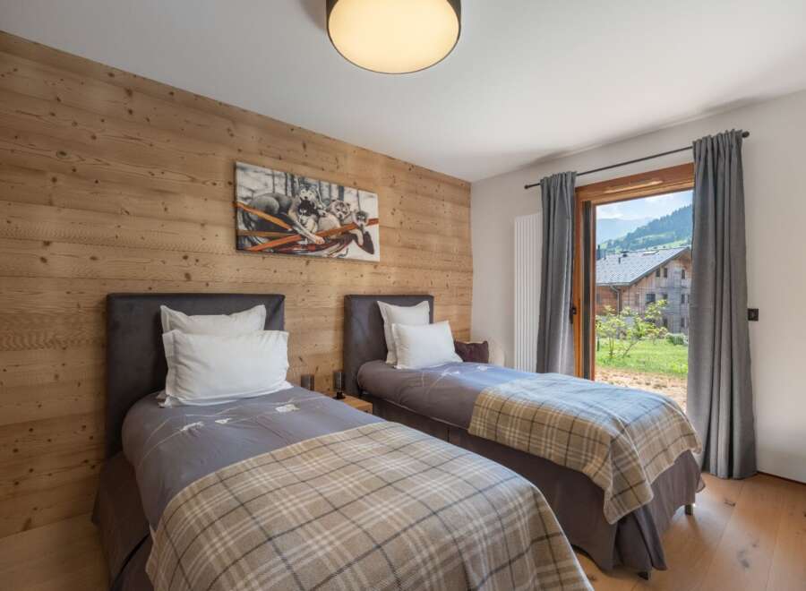 This cozy bedroom features two twin beds with stylish bedding and a warm, inviting atmosphere.