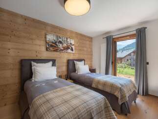 This cozy bedroom features two twin beds with stylish bedding and a warm, inviting atmosphere.