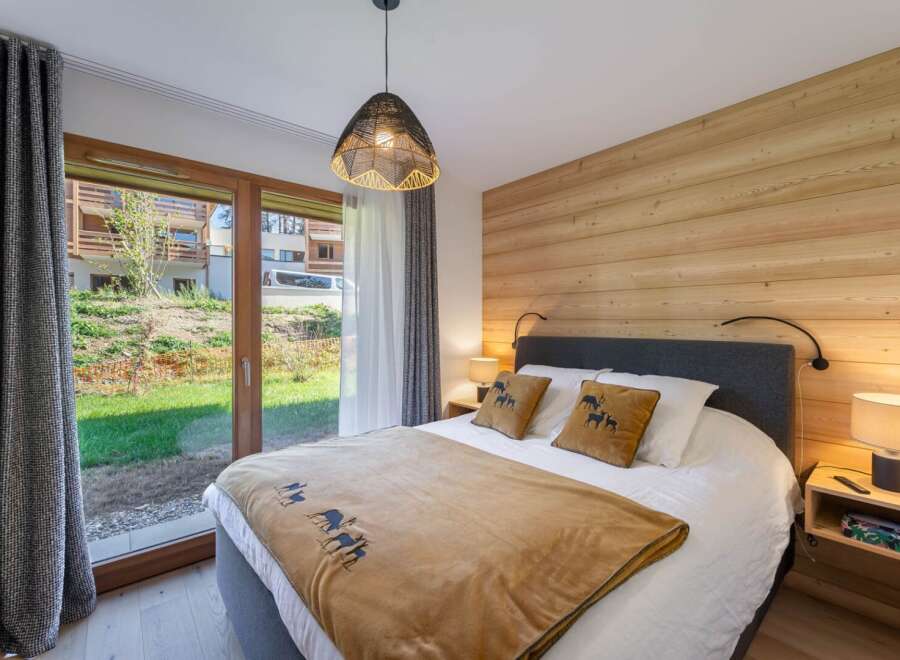 This cozy bedroom features a warm wooden accent wall and a comfortable bed with decorative pillows.