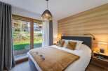 This cozy bedroom features a warm wooden accent wall and a comfortable bed with decorative pillows.