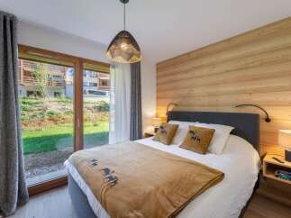 This cozy bedroom features a warm wooden accent wall and a comfortable bed with decorative pillows.