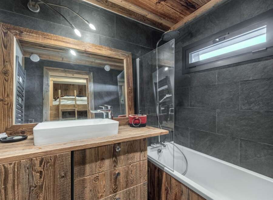 This stunning bathroom boasts a rustic charm with its wooden vanity and mirror frame, creating a warm and inviting atmosphere.