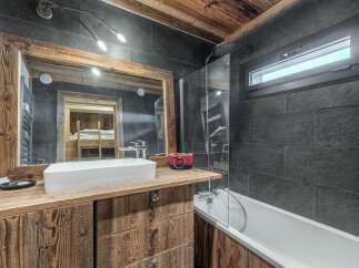 This stunning bathroom boasts a rustic charm with its wooden vanity and mirror frame, creating a warm and inviting atmosphere.