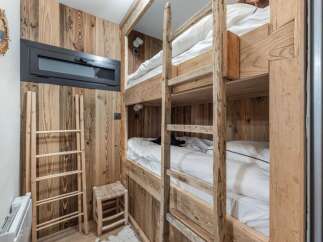 This cozy bedroom features custom-built wooden bunk beds, perfect for accommodating guests or family members.