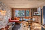 Experience the warmth of this stunning living space, featuring a rustic stone wall and a cozy red sofa, perfect for relaxing after a day on the slopes.