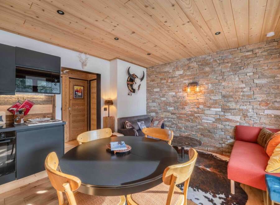 Discover the charm of this cozy living space, featuring a rustic stone wall and a warm wooden ceiling.